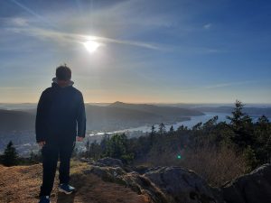 Ung studerende med udsigt over Bergen, fjorde og bjerge i Norge under klart solskin og smuk natur.